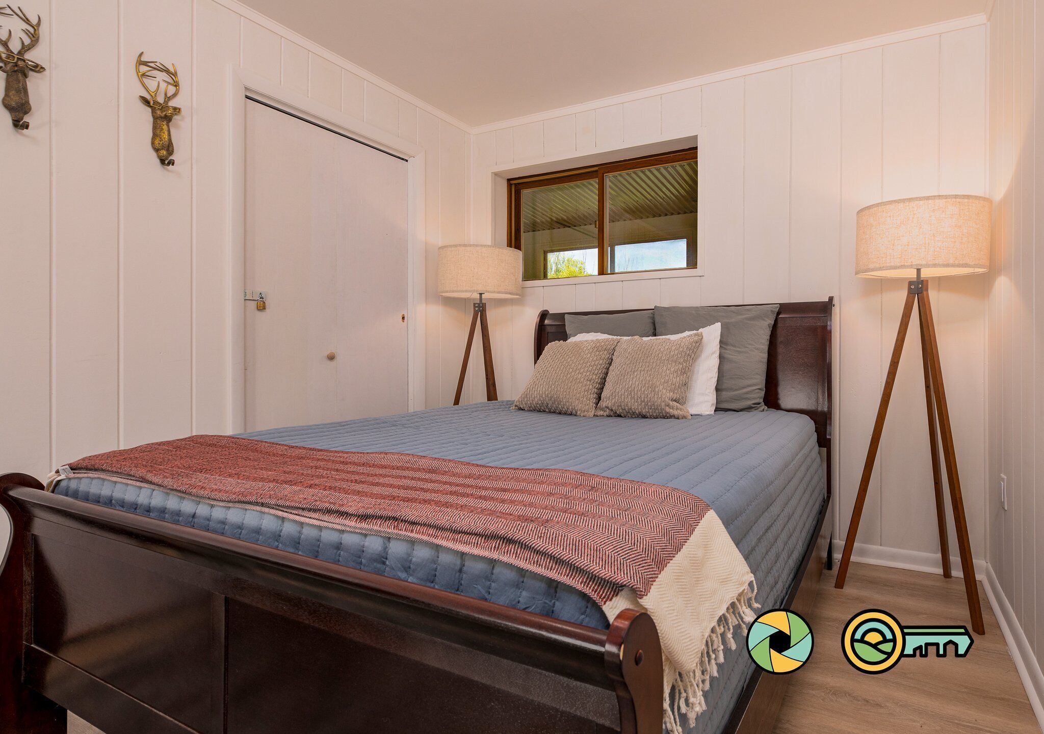 A bedroom with a bed, two bedside lamps, a window, and a door.