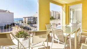 A balcony with a table and chairs, overlooking a street with parked cars and buildings. - El Fenua by Interhome (St Antoni de Calonge)