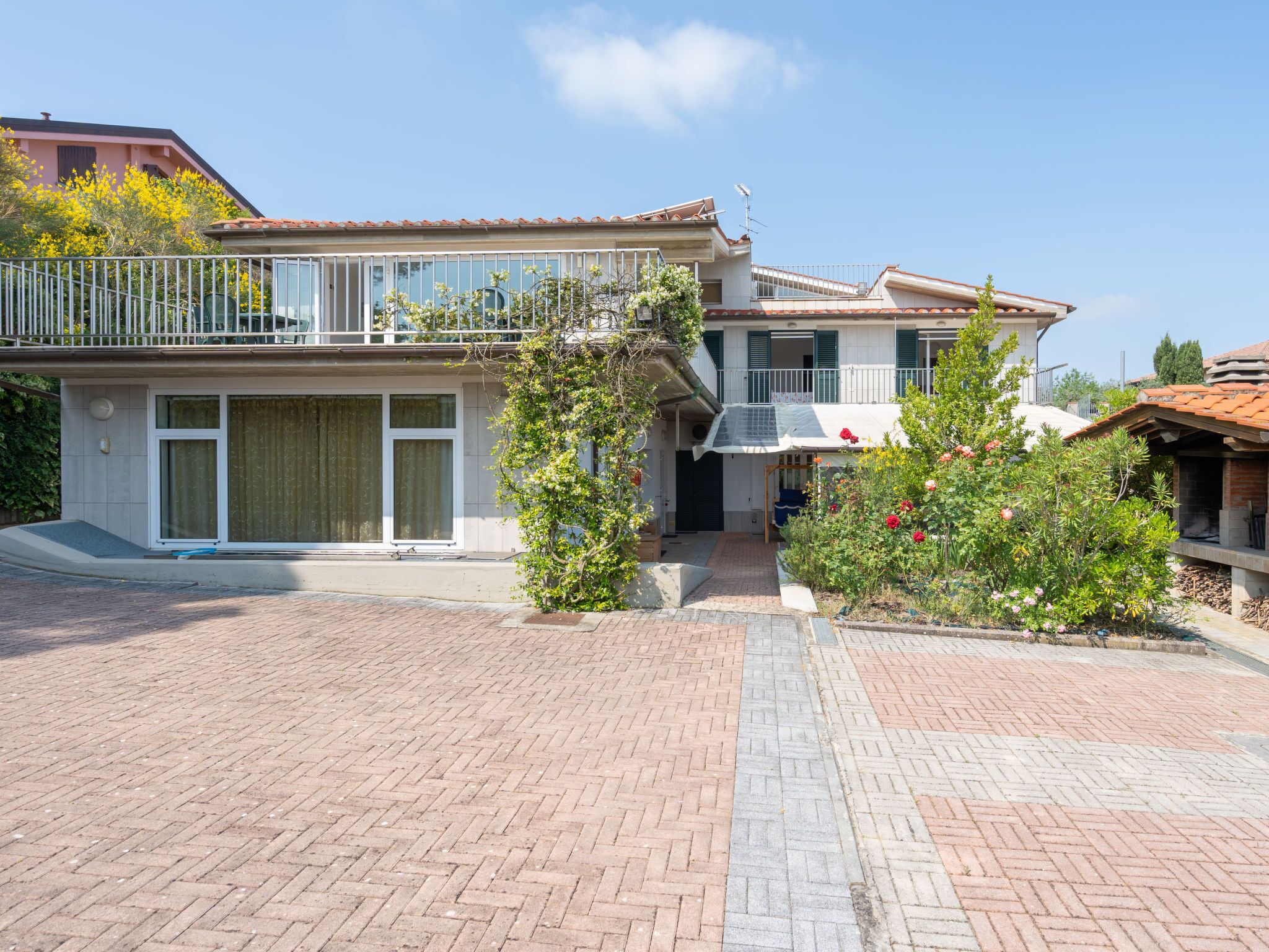 A two-story house with a balcony, a covered entryway, and a brick driveway.