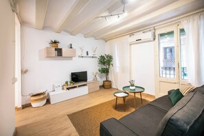 Una sala de estar moderna con una televisión de pantalla plana, piso de madera, un sofá y una planta en maceta.
