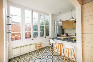 Une cuisine moderne dotée de grandes fenêtres, d’un îlot central et de tabourets de bar.