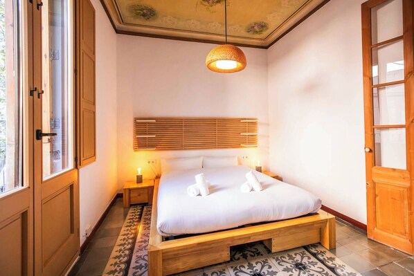 Un dormitorio con cama de madera, una lámpara en el techo y una ventana.