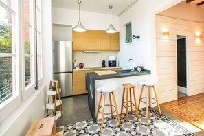 Une cuisine moderne avec des meubles en bois, des appareils en acier inoxydable, un îlot central doté de tabourets et un sol à motifs.