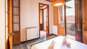 A hotel room with a bed, a radiator, a window with a view, and a hanging light fixture.