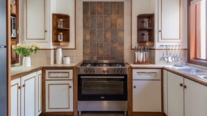 A kitchen with a central stove, oven, and built-in shelves with jars.