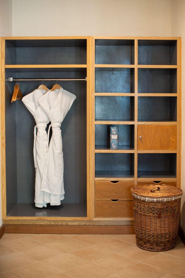 Une armoire en bois dotée de plusieurs étagères et d’un espace pour suspendre des vêtements.