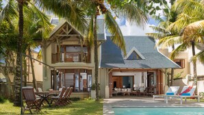 A two-story house with a balcony, a pool, and outdoor seating.