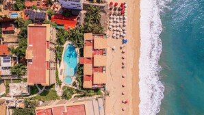 An aerial view of a resort with a swimming pool, beach with umbrellas, and ocean views. - Manta Morada: Mar, San Pancho, Beachfront and Ocean views (San Francisco)