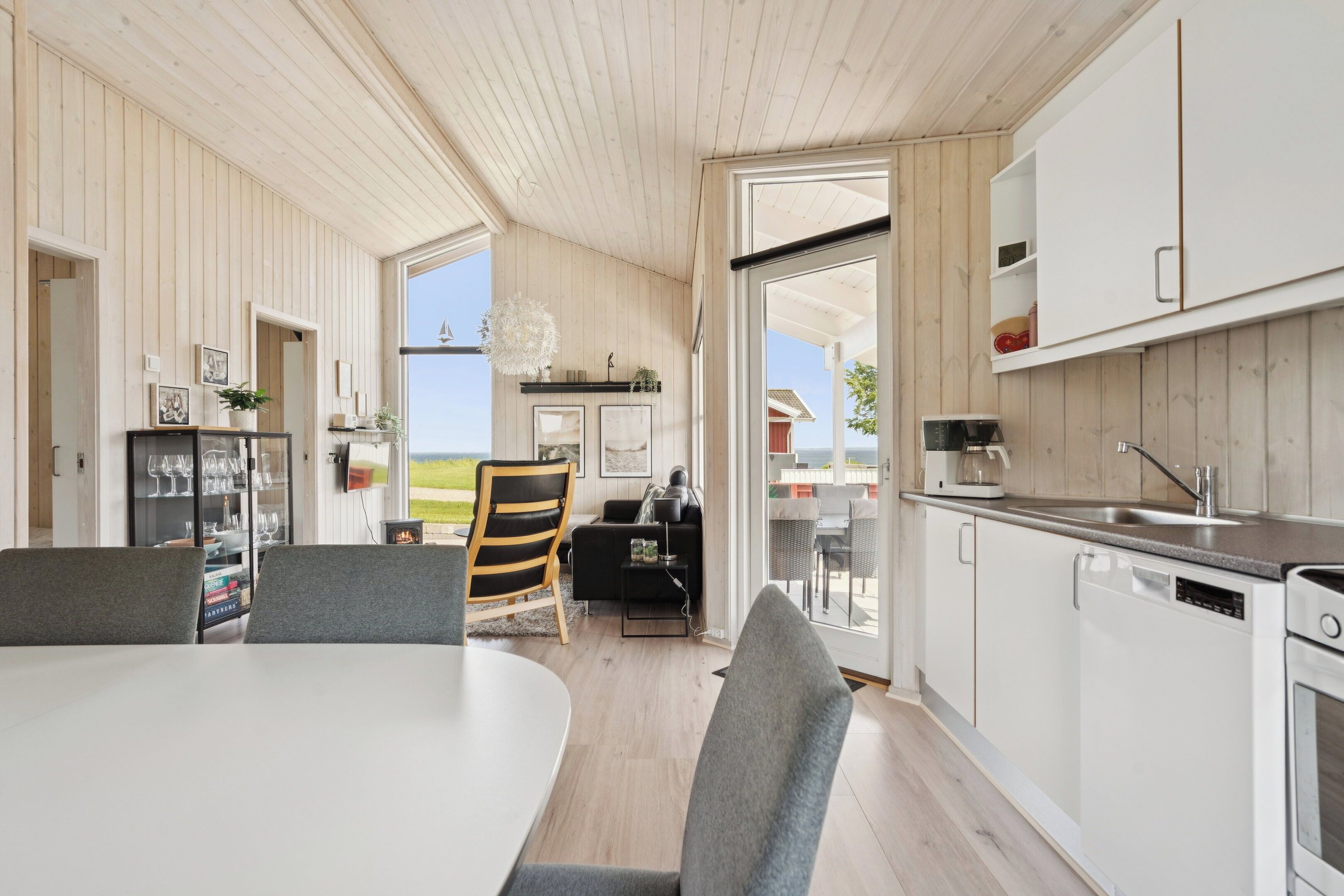 A modern kitchen with white cabinets, a dining area with a table and chairs, and a view of the outdoors.