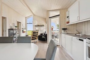 A modern kitchen with white cabinets, a dining area with a table and chairs, and a view of the outdoors.