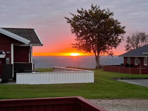 A waterfront property with a view of the sunset, a tree, and a small deck area.