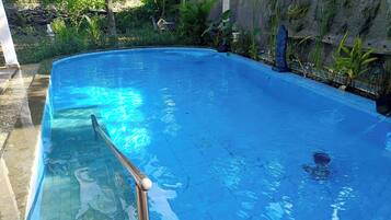 Una piscina al aire libre, sillones reclinables de piscina
