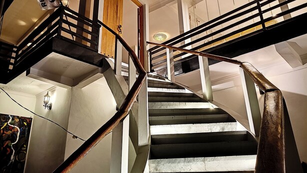 Un escalier en colimaçon avec des rampes en métal et une porte en bois en haut.