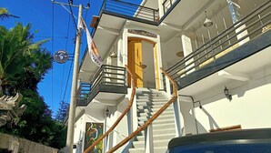 Un bâtiment à deux étages doté d’une porte en bois, d’un escalier et d’un balcon.