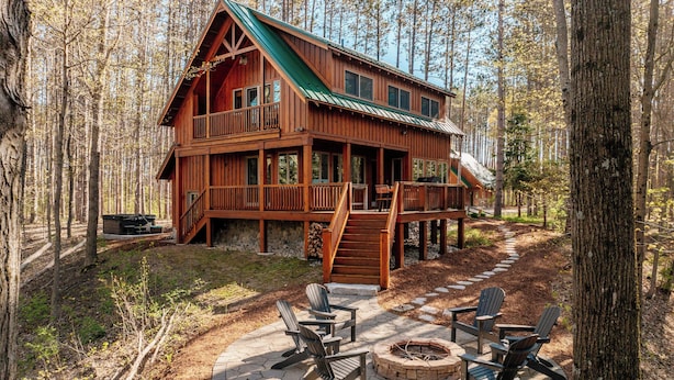 A cabin with a deck, outdoor seating, and a fire pit.