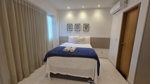 Ein Hotelzimmer mit Bett, Vorhängen, einer Tür und Wandbildern.