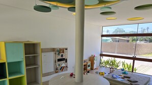 Ein Zimmer mit einem runden Tisch, einem weißen Stuhl und einem farbenfrohen Bücherregal.