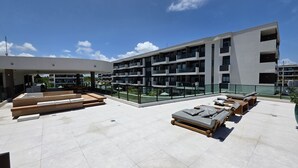 Eine Dachterrasse mit Sitzgelegenheiten im Freien, einem Pool und einem modernen Gebäude mit Balkonen.