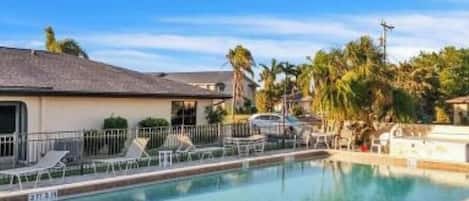 Relax by the pool surrounded by lounge chairs and palm trees.