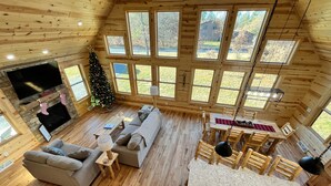 Ein gemütliches Blockhaus-Interieur mit Kamin, Weihnachtsbaum, Sofa und Essbereich.