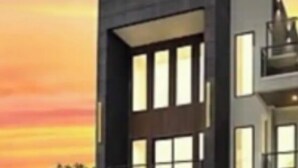 Een modern huis met twee verdiepingen, een garage, grote ramen en een plat dak.