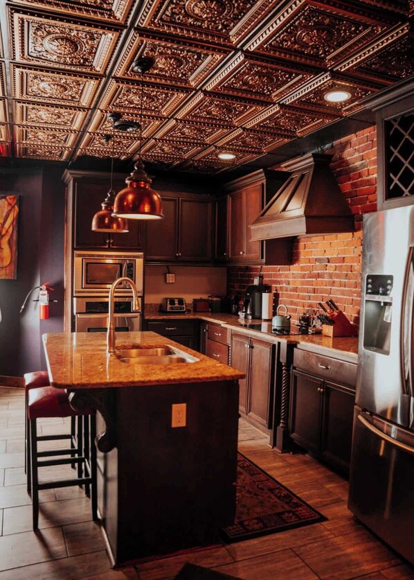 A kitchen with a central island, stainless steel appliances, and a decorative ceiling.