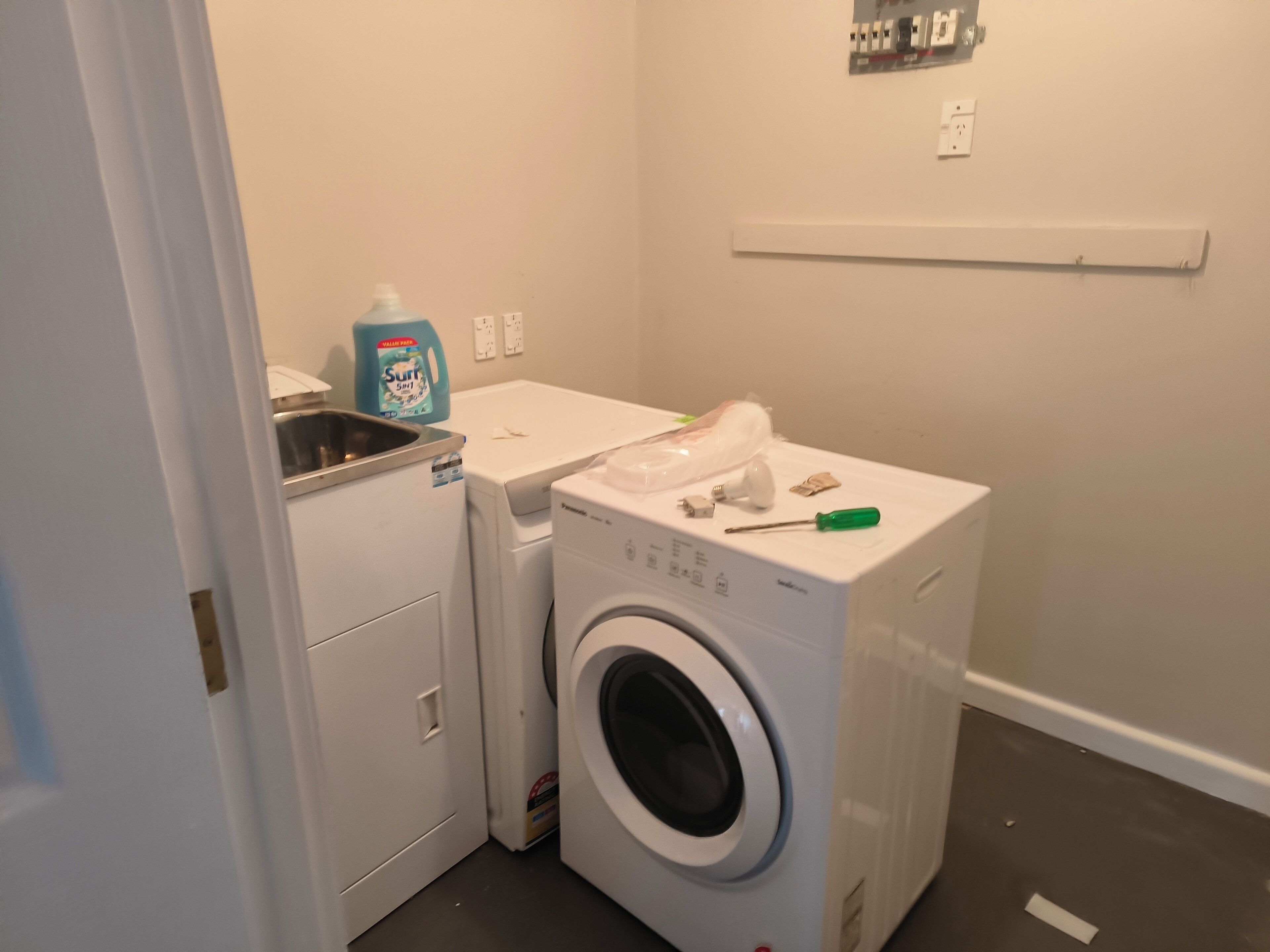 A laundry room with a washing machine, dryer, and a bottle of Surf detergent.