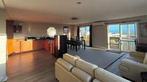 A spacious living area with a sofa, a dining table, and a kitchen area with wooden cabinets and a microwave.