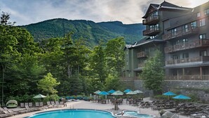 Un resort con piscina, sillas de descanso y vistas a una montaña.