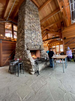 A stone fireplace with a fire, surrounded by wooden beams and stone walls.