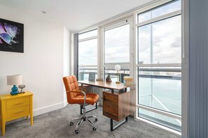 A modern office space with a desk, chair, and a yellow side table with a lamp. - Stunning Thames View 2BR Apartment 2 Baths 2 Balconies Sleeps 6 (Greater London)