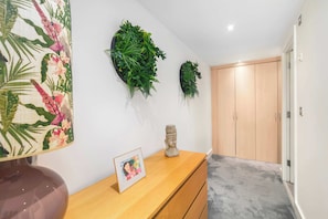 A hallway with a wooden floor, a wooden door, and two wall-mounted green plant decorations.