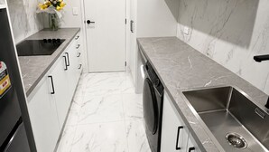 Una cocina moderna con armarios blancos, un lavamanos de acero inoxidable y un lavavajillas integrado.