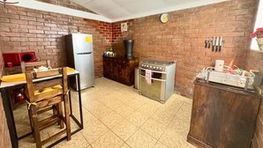 A kitchen with a brick wall, a refrigerator, a stove, and a wooden cabinet.