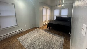 A bedroom with a bed, a rug, and a window.