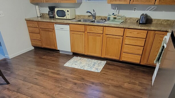 A kitchen with wooden cabinets, a microwave, a toaster, and a dishwasher.