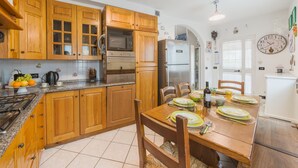 Una cocina con armarios de madera, electrodomésticos de acero inoxidable y un comedor con una mesa preparada para cuatro personas.