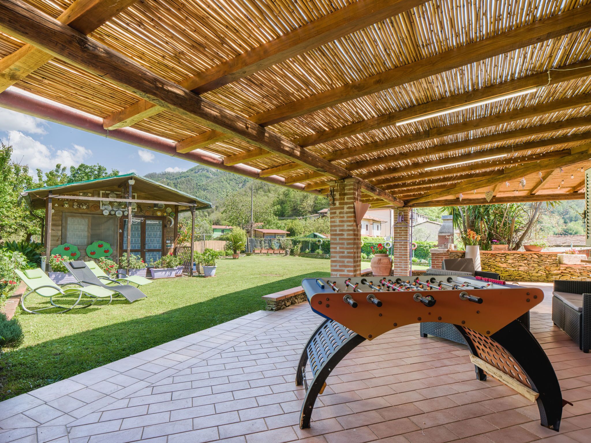 An outdoor patio area with a foosball table, lounge chairs, and a covered seating area.