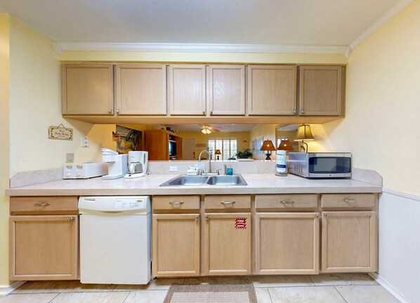 A kitchen with wooden cabinets, a dishwasher, a microwave, and a coffee maker.