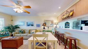 A modern kitchen with a dining area, featuring a ceiling fan, a refrigerator, and a bar area. - Shared Pool, Pet Friendly, Garage Access (Port Aransas)