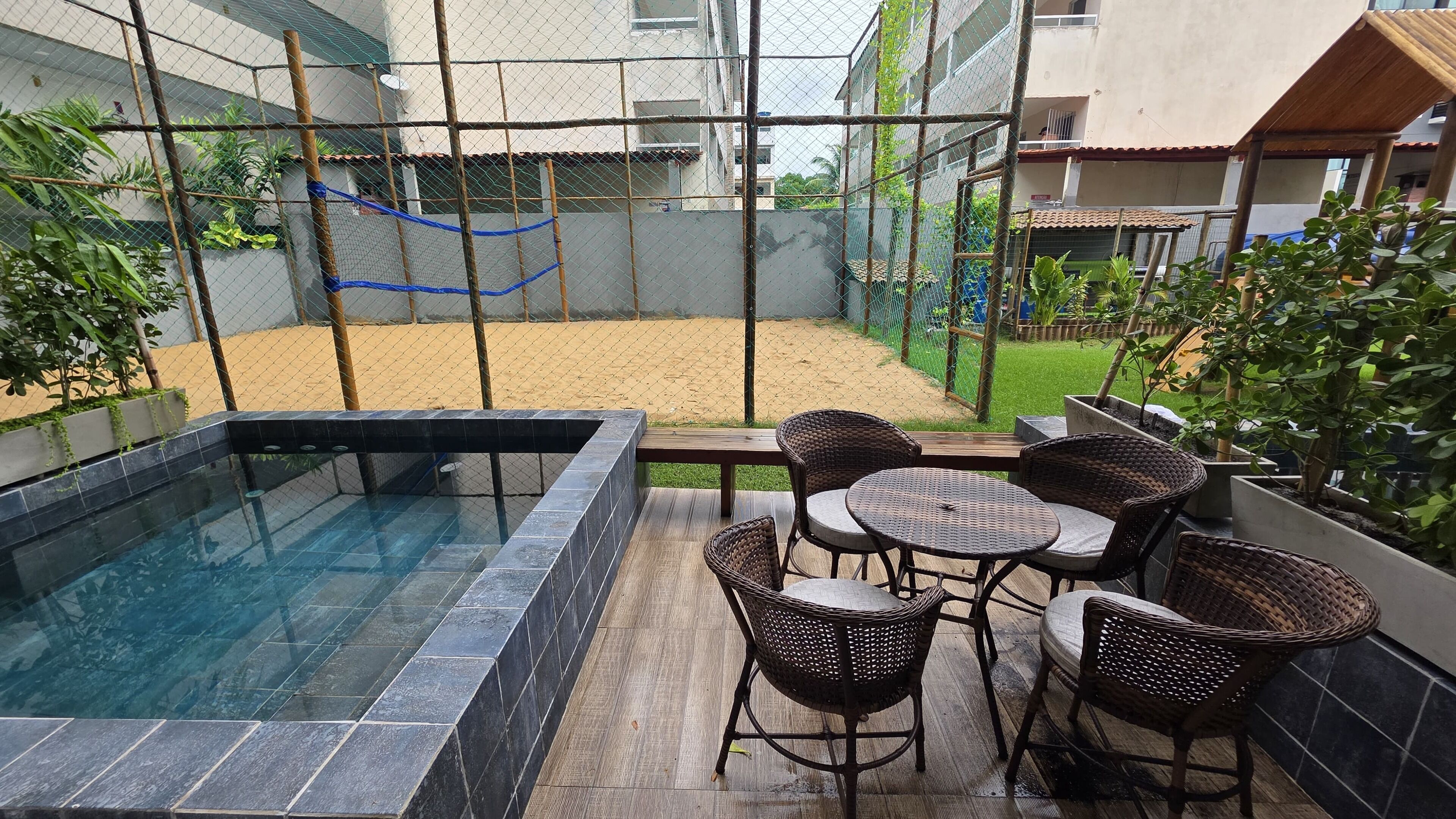 A swimming pool with a wooden deck and wicker chairs.