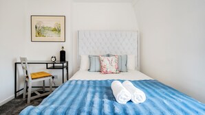 Una camera da letto ordinata con un letto, una scrivania e una sedia.