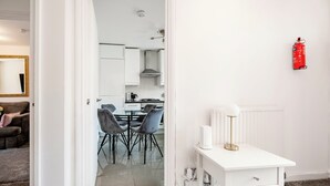Una cucina moderna con mobili bianchi, un fornello a gas e un estintore rosso appeso al muro.