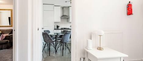 A modern kitchen with white cabinets, a gas stove, and a red fire extinguisher on the wall.