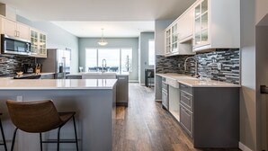 A modern kitchen with a central island, grey cabinetry, and a view to the outside. - 2 Side-by-Side Ski-In/Ski-Out Townhomes | Sleeps 19 w/ Views (Silver Star Mountain)