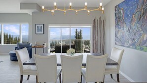 A modern dining area with a large table and chairs, a chandelier, and a painting on the wall. - 2 Side-by-Side Ski-In/Ski-Out Townhomes | Sleeps 19 w/ Views (Silver Star Mountain)