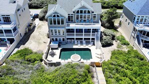 Une grande maison à deux étages dotée d’une piscine, de plusieurs terrasses et d’un quai.