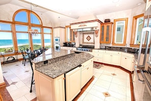 A spacious kitchen with a large island, a dining area with a view, and a view of the ocean.