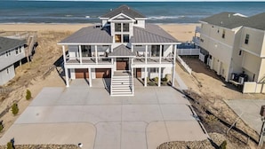 A beachfront house with a large deck, multiple balconies, and a view of the ocean. - A Wave From It All | Oceanfront | Hot Tub (Virginia Beach)