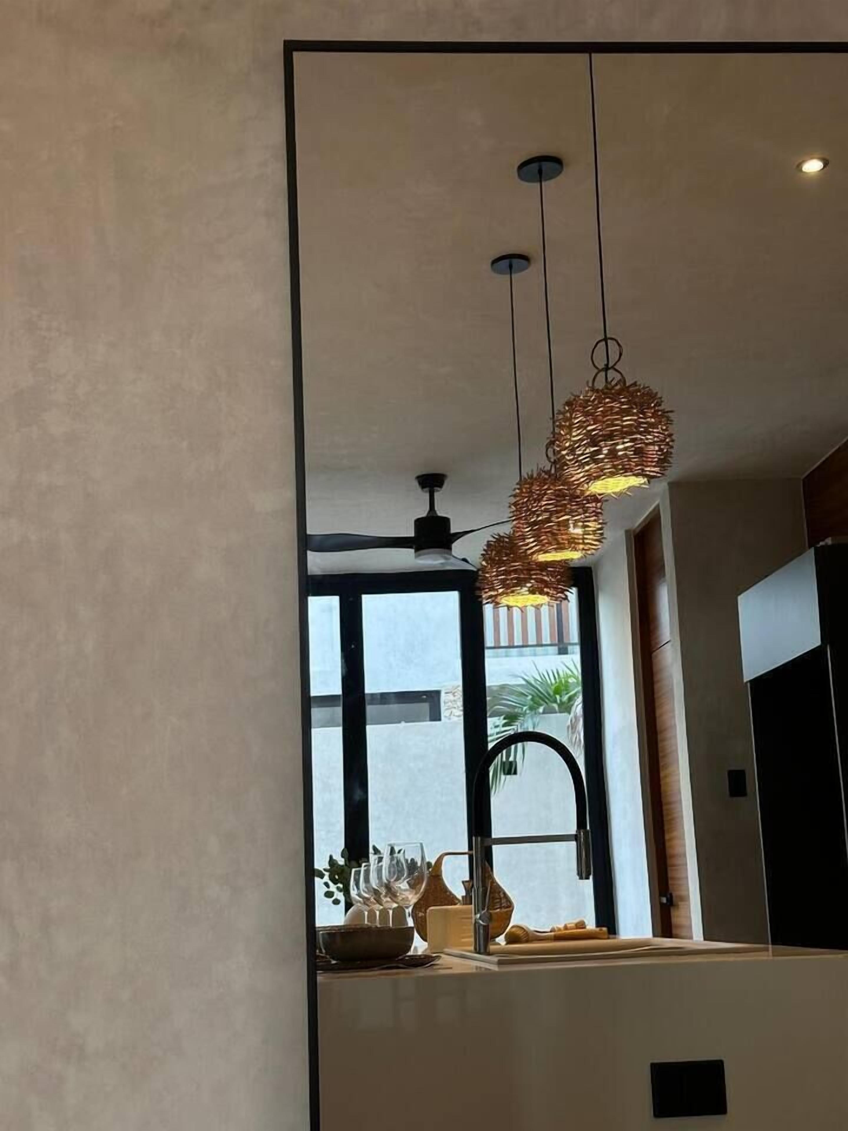 A modern kitchen with a large window, a ceiling fan, and a unique woven light fixture.